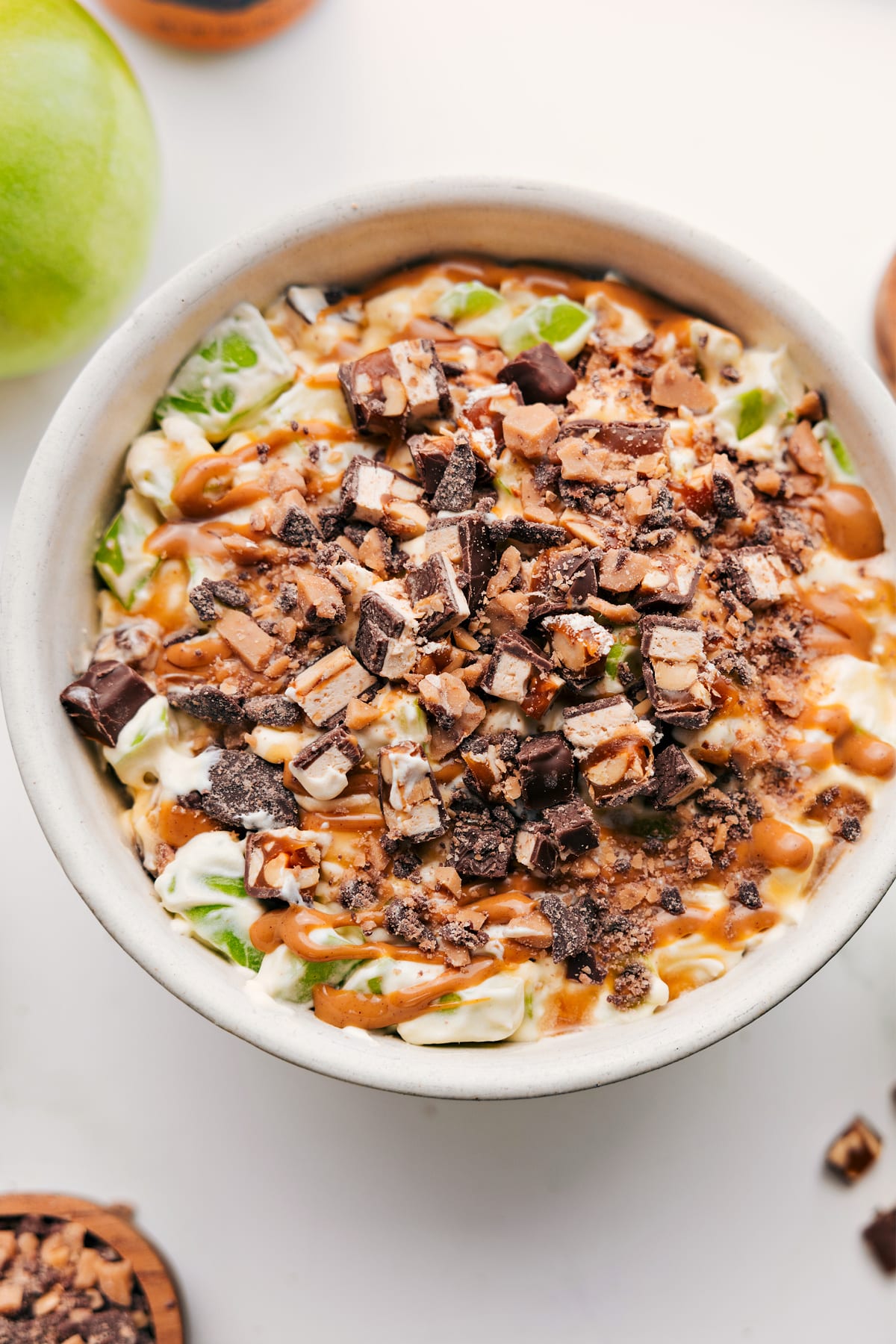 Snickers Salad Recipe in a bowl topped with chopped Snickers and a drizzle of caramel sauce
