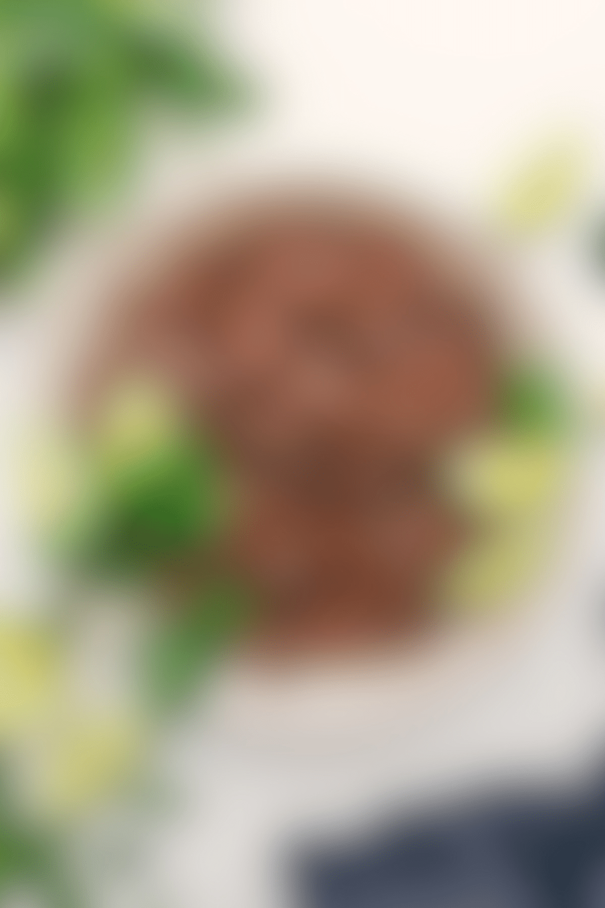 Chipotle beef barbacoa in a bowl with fresh cilantro and lime wedges on the side.