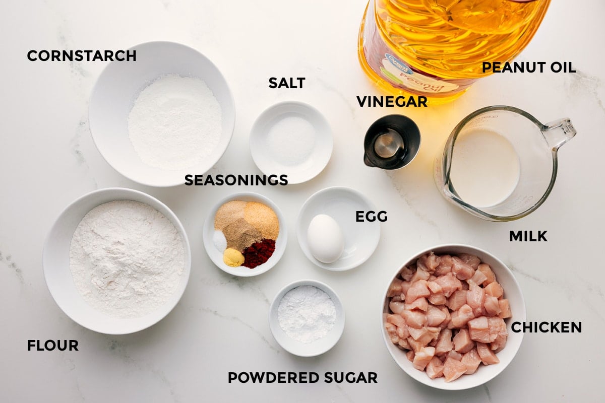 Ingredients In Chick-Fil-A Nuggets Recipe All the ingredients in this recipe prepped out for easy assembly including the cornstarch, flour, seasonings, salt, powdered sugar, egg, vinegar, peanut oil, milk, and chicken.