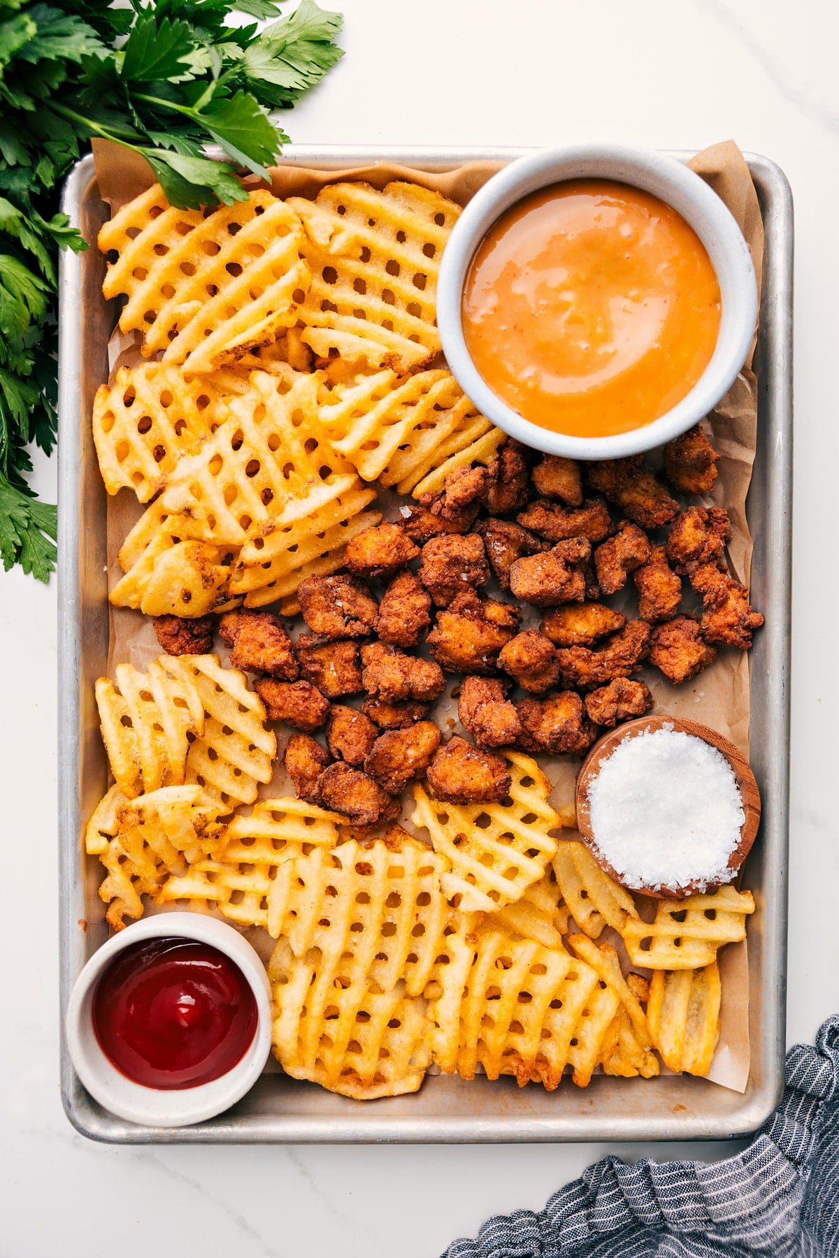 Chick-fil-A Nuggets Recipe served on a sheet pan with fries and dipping sauce on the side.